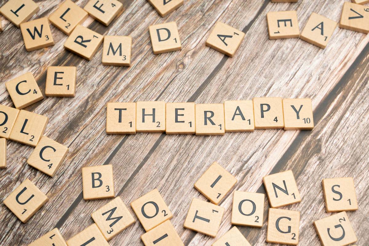 A therapist reviewing a tablet showing a waveform analysis overlay beside a 'therapy playlist activity' label